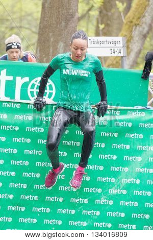 STOCKHOLM SWEDEN - MAY 14 2016: Woman jumping out of a tank of ice cold water in the Ice cube obstacle in the obstacle race Tough Viking Event in Sweden May 14 2016