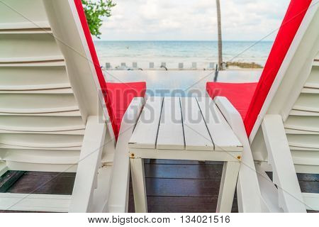 Beautiful beach chairs with umbrella around outdoor swimming pool neary sand and sea