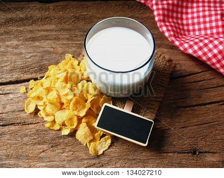 milk and corn cereals with small wooden for text on old table
