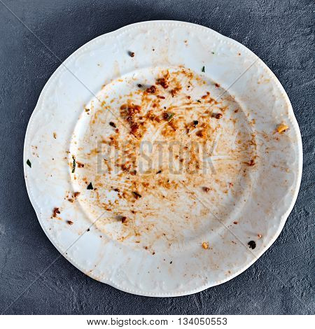 White dirty plate after spaghetti pasta with meat and tomato sauce. Red sauce spots on dish area. Stone background