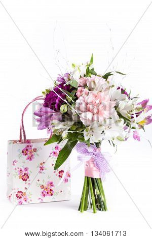 Pastel bouquet from pink and purple gillyflowers and alstroemeria on white background with gift