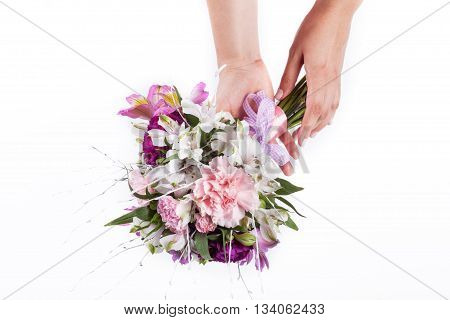 Hands holding a bouquet from pink and purple gillyflowers and alstroemeria