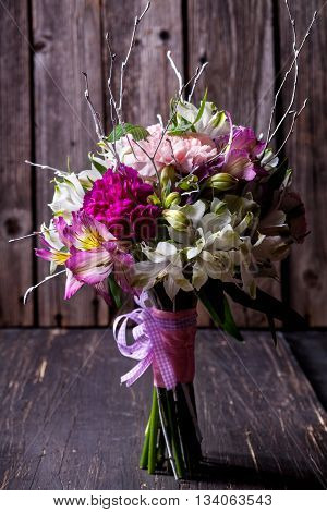 Pink bouquet from gillyflowers and white alstroemeria on old wooden background