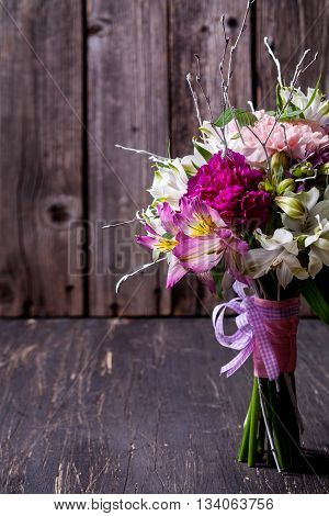 Pink bouquet from gillyflowers and white alstroemeria on old rustic wooden background