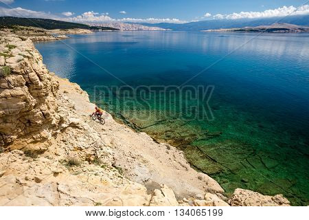 Mountain biker riding a bike at the seaside and mountains landscape. Man cycling MTB on enduro trail dirt path. Sport fitness motivation and inspiration in beautiful environment.