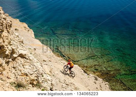 Mountain biker riding a bike at the seaside and mountains landscape. Man cycling MTB on enduro trail dirt path. Sport fitness motivation and inspiration in beautiful environment.
