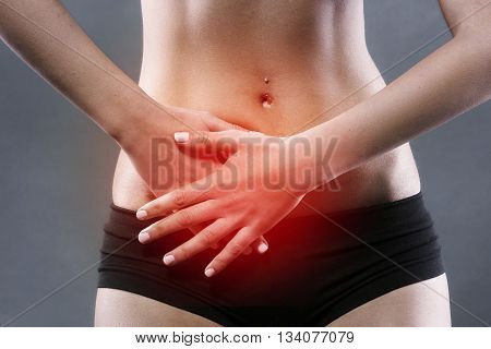 Body pain. Close up studio shot of woman. Woman suffering from underbelly pain. Red spot on underbelly