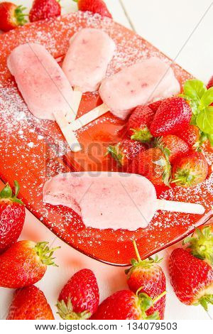 Homemade ice cream popsicles with fresh strawberries. Light organic summer dessert with ripe berries.
