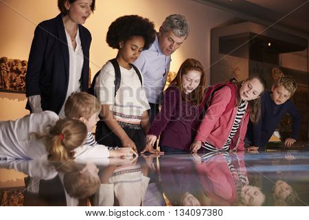 Pupils On School Field Trip To Museum Looking At Map