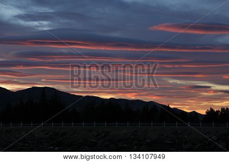 Sunrise in Hawea New Zealand. Colorful clouds over a mountain range.