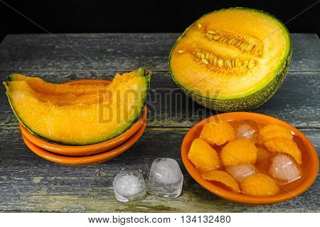 Fresh cantaloupe melon and ice on dark background copy space hot summer concept