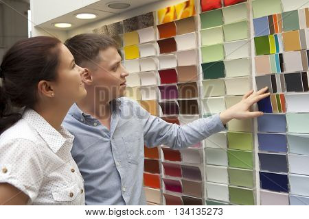 Happy couple family select paint color and look matching samples at household store