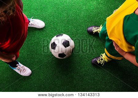 Two Unrecognizable Little Football Players Against Green Grass
