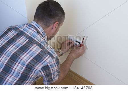 Electrician installing new current socket with screwdriver. Installing electrical outlet or socket - closeup on electrician hands