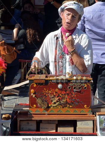 PARIS FRANCE OCT 17 2014: Street artist Arlette Denis (Macadam Manivelle) singing and playing barrel organ at Montmartre. Arlette Denis started singing in 1968.