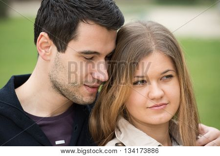 young couple man and woman sitting and hugging man is wispering