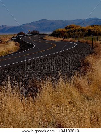 A winding road in Southeast Oregon hits the top of the hill on a nice fall day.
