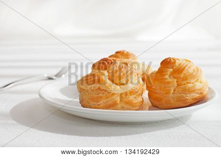 Profiteroles, choux with a custard cream, creme anglaise, whipped cream, dessert on a white plate Copy space