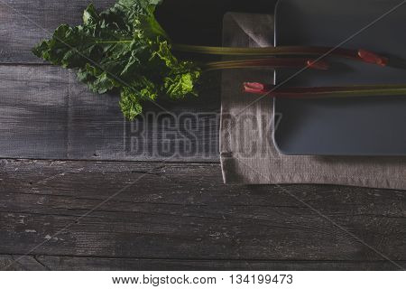 Organic pieplant lying on gray plate and old wooden table