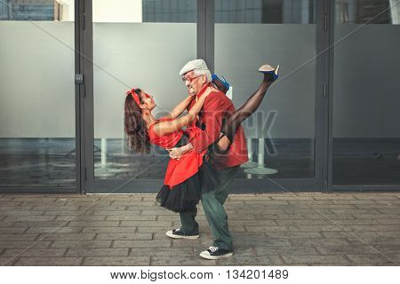 The old man holds the young woman on hands they dance.