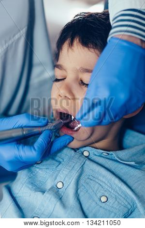 Dentist drilling little boy's tooth in dentis office