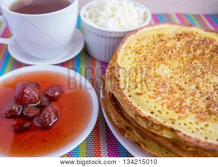 Pancakes with strawberry jam cheese and cup of tea.