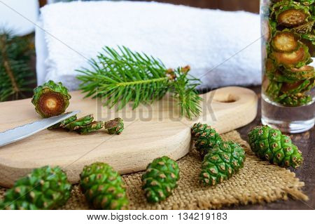 Young green fir cones on the wooden background. Chopping knife cones for making medicinal infusion.