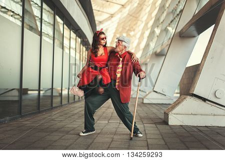 Young girl is dancing with the old man they are dressed in retro clothes.