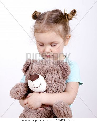 little blond girl hugging a teddy bear