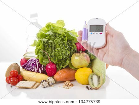 Diabetes concept glucose meter in hand and healthy organic food