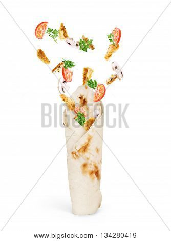 Vegetables with chicken in flight falls on pita bread on a white background