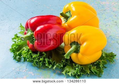 Fresh organic red and yellow bell peppers and lettuce on old blue table. Selective focus