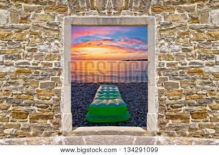 Sunset on beach through stone wall door view village of Petrcane Dalmatia Croatia