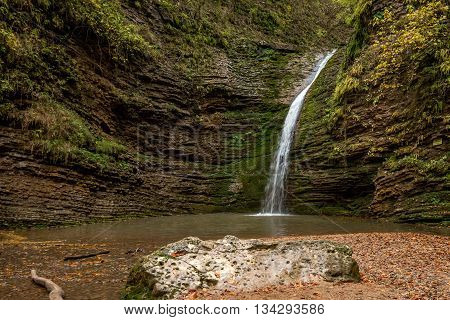 Beautiful landscape with forest waterfall and lush foliage in autumn