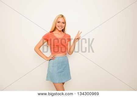 Cherrful Girl In Blue Skirt Gesturing With Two Fingers