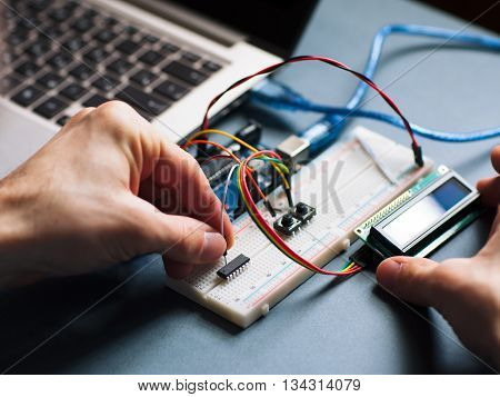 Microchip manual connecting to microcontroller. Top view on engeneer hands working with microcontroller. Closeup of microcontroller