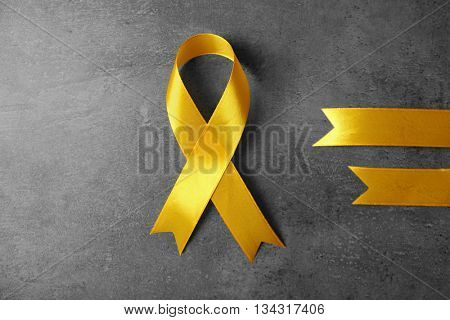 Yellow awareness ribbon on grey textured background