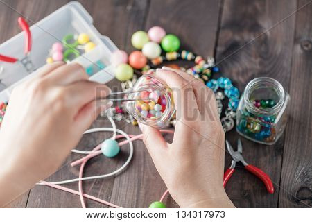Woman take one bead for making home craft bead art