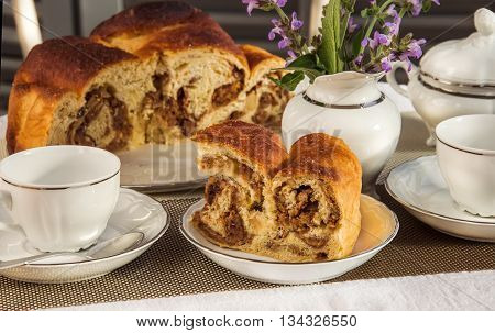 Typical italian flavorous home baked cake La Gubana with sophisticated stuffing (hazelnuts fruit chocolate walnut raisins honey etc.) with purple flowers of salvia on the table covered for breakfast. Traditionally bake for Christmas and Easter.
