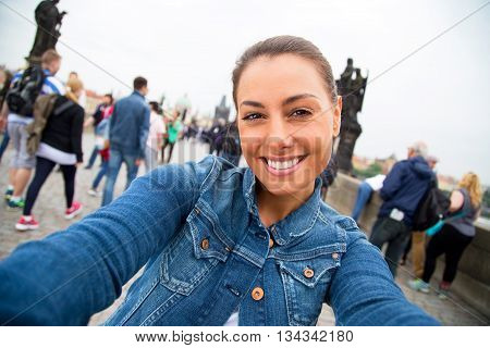 young woman taking a selfie on charles bridge in Prague