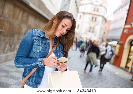 young woman reading her text messages in the street