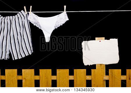 Woman panties and man underwear on clothesline on black background