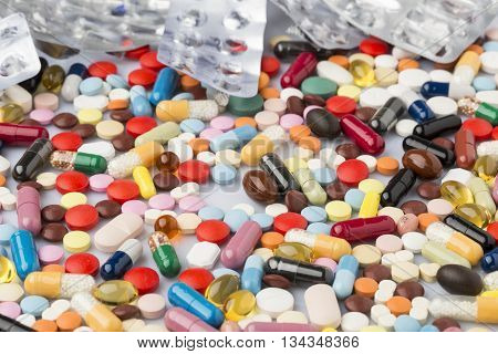 Pharmaceutical background of multi-colored tablets and capsules scattered on the surface