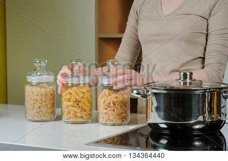 Woman cooking. Thre Closed Glass Jar With Raw Pasta. Woman is going to cook pasta.