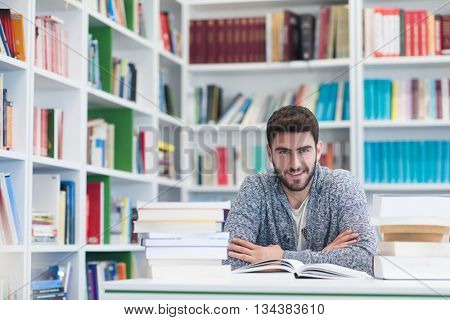 Portrait of happy student while reading book in school library. Study lessons for  exam. Hard worker and persistance concept.