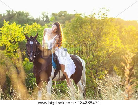 Young woman riding a horse at sunset
