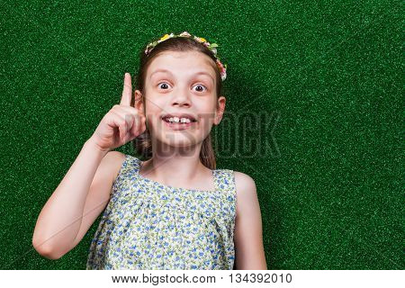 Little girl is lying on artificial grass. She is having an idea.