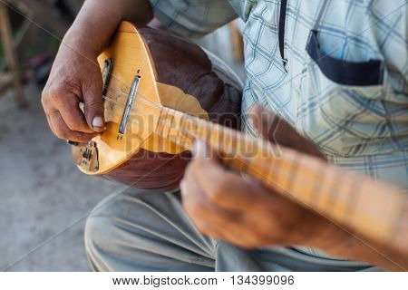 Close up shot of a man playing a Tatar instrument called 