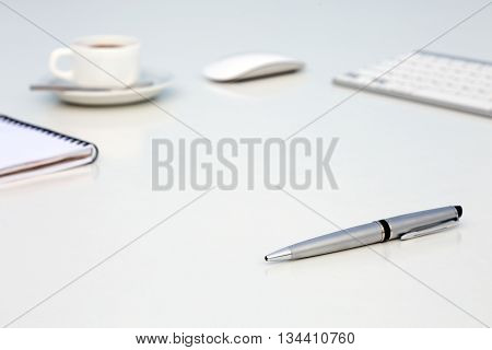 Bright Open Space Office White Table Angle View with Coffee Mug Opened Blank Notepad Pen and Computer Keyboard and Mouse on Desk