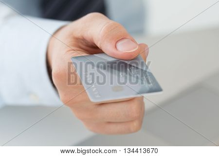 Close up view of business man hand holding credit card. Online payments e-commerce internet banking shopping delivery anti-fraud or financial security concept.